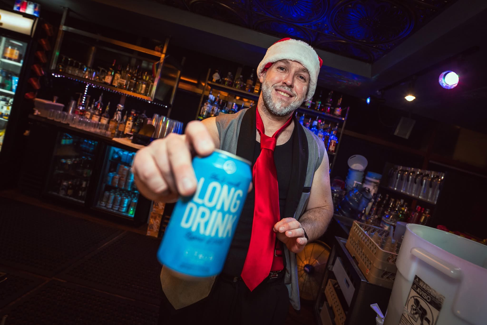 Hookava bartender in Santa hat holding Long Drink can at the bar during a Crawl Reno event
