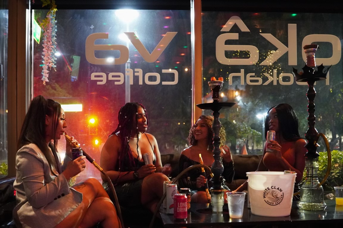 Group of four women laughing and enjoying hookah and drinks at Hookava lounge