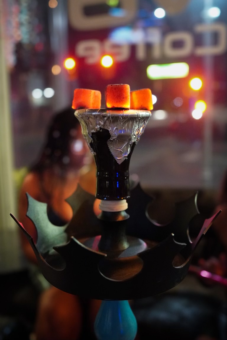 Hookah bowl with glowing coals at Hookava with Downtown Reno neon lights in the background