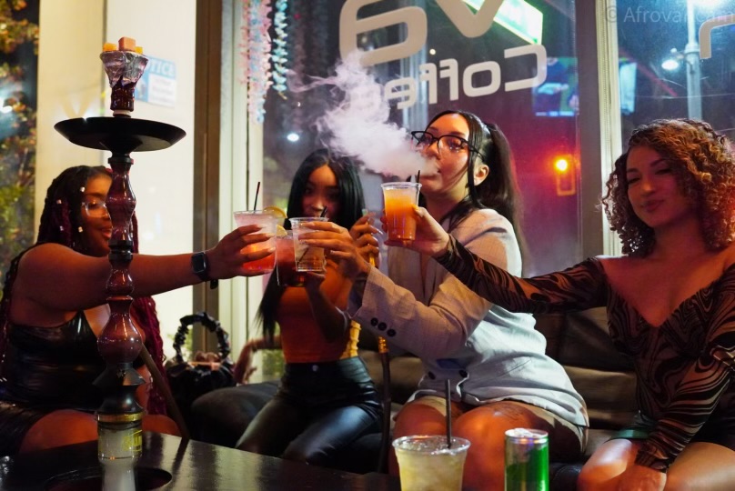 Group of women toasting drinks and blowing hookah smoke at Hookava lounge